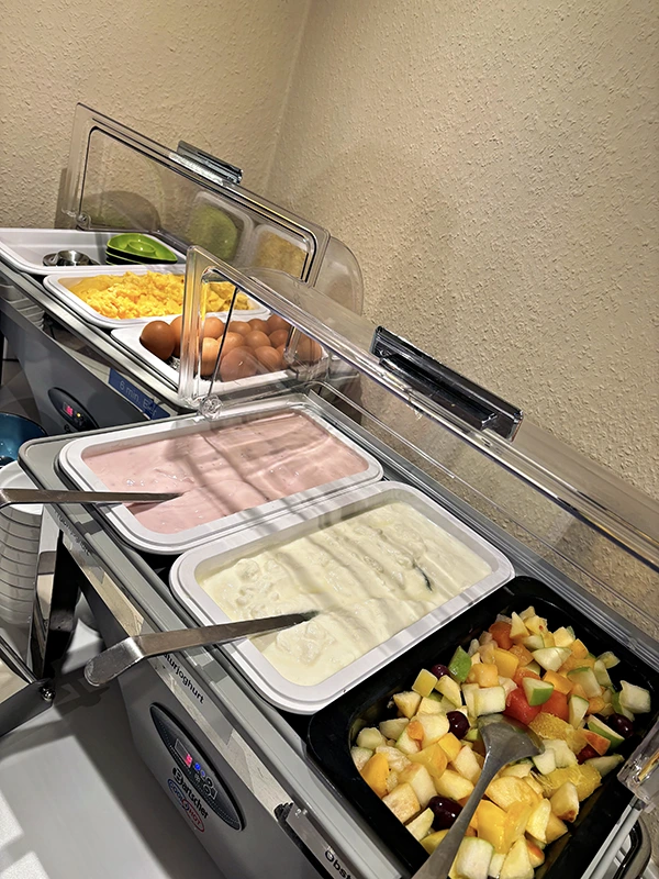 Mit frischen Obstsalat und Joghurts, Rührei und Speck.